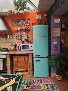 a blue refrigerator sitting in the middle of a kitchen next to a potted plant