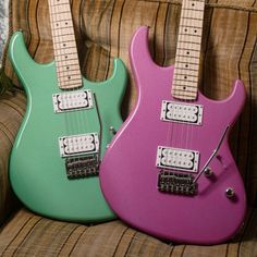 two electric guitars sitting side by side on a couch