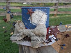 a bow tie on top of a blue trash can sitting on a wooden bench in front of a fence