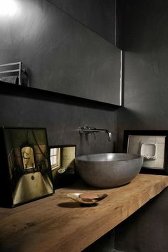 a bowl sink sitting on top of a wooden counter next to a framed photo and mirror