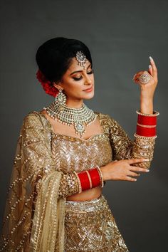 a woman in a gold and red outfit holding something up to her right side with both hands