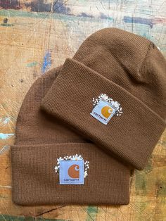 two brown beanies sitting on top of a wooden table next to each other,