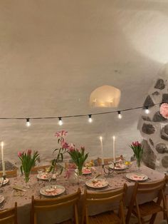 a long table with flowers and candles is set up for a formal dinner in a stone walled room