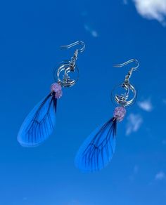 a pair of earrings with blue feathers hanging from it's earwires against a blue sky background