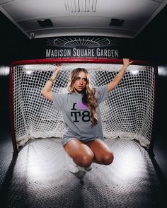 a woman sitting on the ground in front of a goalie net with her arms up