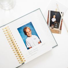 an open photo album with a child's picture on it and a pencil next to it