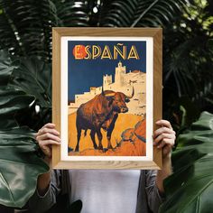 a woman holding up a framed poster with an image of a bull in the background