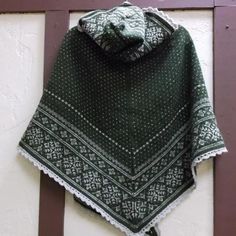 a green and white shawl hanging on the side of a building with a wooden door