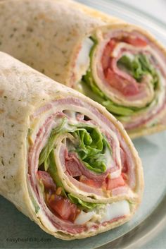 two wraps with meat, lettuce and tomato on them sitting on a plate