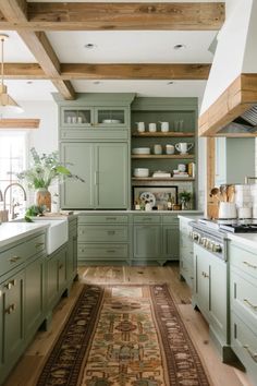 a kitchen with green cabinets and rug in the middle of the floor, along with wooden beams on the ceiling