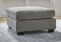 a gray ottoman sitting on top of a rug