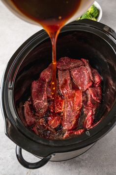 the meat is being poured into the slow cooker to make it easier to cook