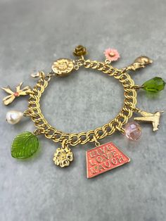 WHAT IT IS: A "Girly Garden" themed charm bracelet featuring 10k gold plated chain, a vintage solid brass box clasp, hand-enameled vintage brass charms, a freshwater pearl, a vintage pressed glass leaf, and Austrian crystals.  THE SPECS: - 7.5 inches total length. - Box clasp closure. WHY IT'S SPECIAL: This bracelet draws inspiration from one of Mary's children's favorite bedtime stories: Beatrix Potter's "The Tale of Peter Rabbit"...thought it's not Peter who serves as the inspiration, but his three sisters--Flopsy, Mopsy, and Cottontail--in their coral-colored coats (we love that there are three, like us!). The dangling charms include (of course) a rabbit, along with a hummingbird and flowers that might be seen in Mr. McGregor's garden. We hand-enameled the brass bow with a coral center Whimsical Metal Jewelry With Vintage Charm, Whimsical Vintage Charm Jewelry, Whimsical Gold Jewelry With Flower Charm, Enamel Charms Bracelet, Enamel Charms Bracelets For Gift, Whimsical Gold Jewelry With Lobster Clasp, Enamel Bracelet Jewelry With Lobster Clasp, Enamel Bracelet With Lobster Clasp, Whimsical Gold Charm Bracelet