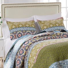 a bed with a white headboard and colorful bedspread