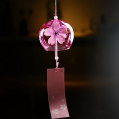 a pink glass ornament hanging from a string with a tag attached to it