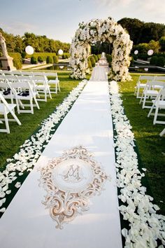 the aisle is decorated with white flowers and greenery