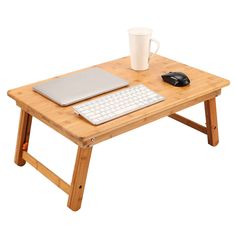 a computer desk with a laptop, keyboard and mouse on it next to a cup of coffee