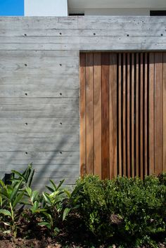 a wooden fence next to a building with plants in front of it and a fire hydrant on the side