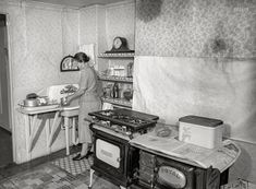 an old black and white photo of a woman in the kitchen