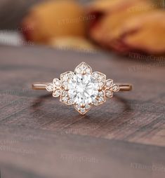 an engagement ring with a flower design on the front and side, sitting on a wooden surface