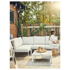 a woman sitting on top of a white couch next to a table with drinks in it