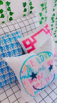 four decorative pillows on a tiled surface with ivy growing in the backgroung