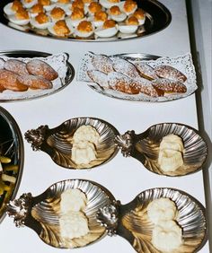 an assortment of pastries and desserts are on display in silver dishes, along with other food items