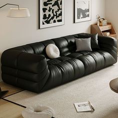 a black leather couch sitting in a living room next to two pictures on the wall