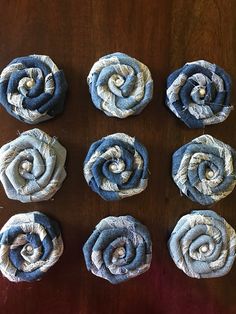 six rolled up fabric flowers sitting on top of a wooden table