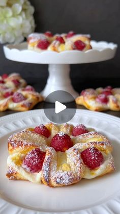 a white plate topped with pastries covered in powdered sugar and raspberries