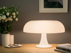 a white lamp sitting on top of a wooden table next to a vase with flowers