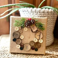 a close up of a small box with buttons and pine cones on the front, sitting on a table next to a potted plant