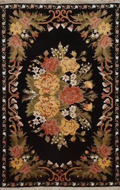 a black rug with orange and yellow flowers on the center, surrounded by other floral designs