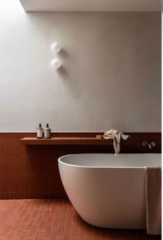 a white bath tub sitting in a bathroom next to a sink and counter top with soap dispensers on it