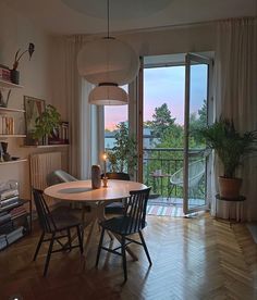 a dining room with a table and chairs next to an open door that leads to a balcony