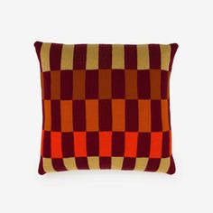 an orange and red pillow with squares on it's sides, against a white background