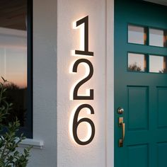 a house number sign on the side of a building with a green door and potted plant next to it