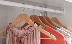 clothes hanging on wooden hangers in a closet