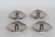 four pieces of metal sitting on top of a white surface