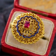 This highly detailed ring from Italy has ornate pierced goldwork accented by an undulating blue enamel border, and centered with a rectangular step cut ruby. The rich color of the gold has a very luxurious feeling. The ring is crafted in 14k yellow gold and is currently a size 6. Please note that the ruby has natural surface-reaching inclusions and that there is a slight nick in the blue enamel, neither of which affects wearability. Vintage Gold Enamel Ring With Gemstone, Luxury Gold Ruby Ring With Intricate Design, Victorian Enamel Ring For Formal Occasions, Vintage Yellow Gold Enamel Ring With Gemstone, Antique Yellow Gold Enamel Ring For Ceremonies, Antique Yellow Gold Enamel Ring For Ceremonial Occasions, Victorian Ruby Ring In Yellow Gold With Intricate Design, Victorian Yellow Gold Ruby Ring With Intricate Design, Ceremonial Yellow Gold Ruby Ring With Intricate Design