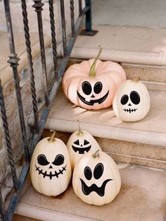 three pumpkins with faces painted on them sitting on the steps