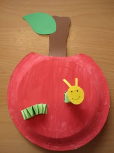 a paper plate with an apple cut out to look like a caterpillar on it