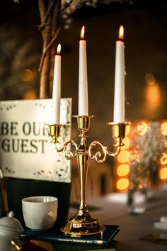 three candles are lit on a table with tea cups