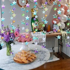 a table topped with cake and stars hanging from the ceiling next to plates filled with pastries