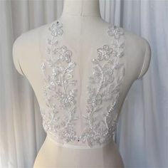 the back of a white dress on a mannequin with silver beads and sequins