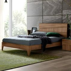 a bedroom with a bed, nightstands and green carpeted flooring in front of a stone wall