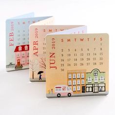 three calendars with different designs on them sitting in front of a white background and one has an image of a bus