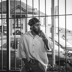 a man standing in front of a fence with his hand to his mouth and looking at the camera