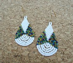 Hello! Dangle drop fringe brick stitch earrings made with 11/0 miyuki seed beads in white and galactic blue gold mix. They measure 2 1/2''long x 1''wide and they hang from surgical steel gold plated earrwires. Nickel and lead free materials. THANKS! White Bohemian Earrings With Spacer Beads, Bohemian White Beaded Earrings With Spacer Beads, Stitch Earrings, Brick Stitch Earrings, Beaded Earrings Patterns, White Brick, Earrings Drop, Earring Patterns, Brick Stitch