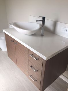 a white sink sitting on top of a wooden cabinet next to a toilet in a bathroom